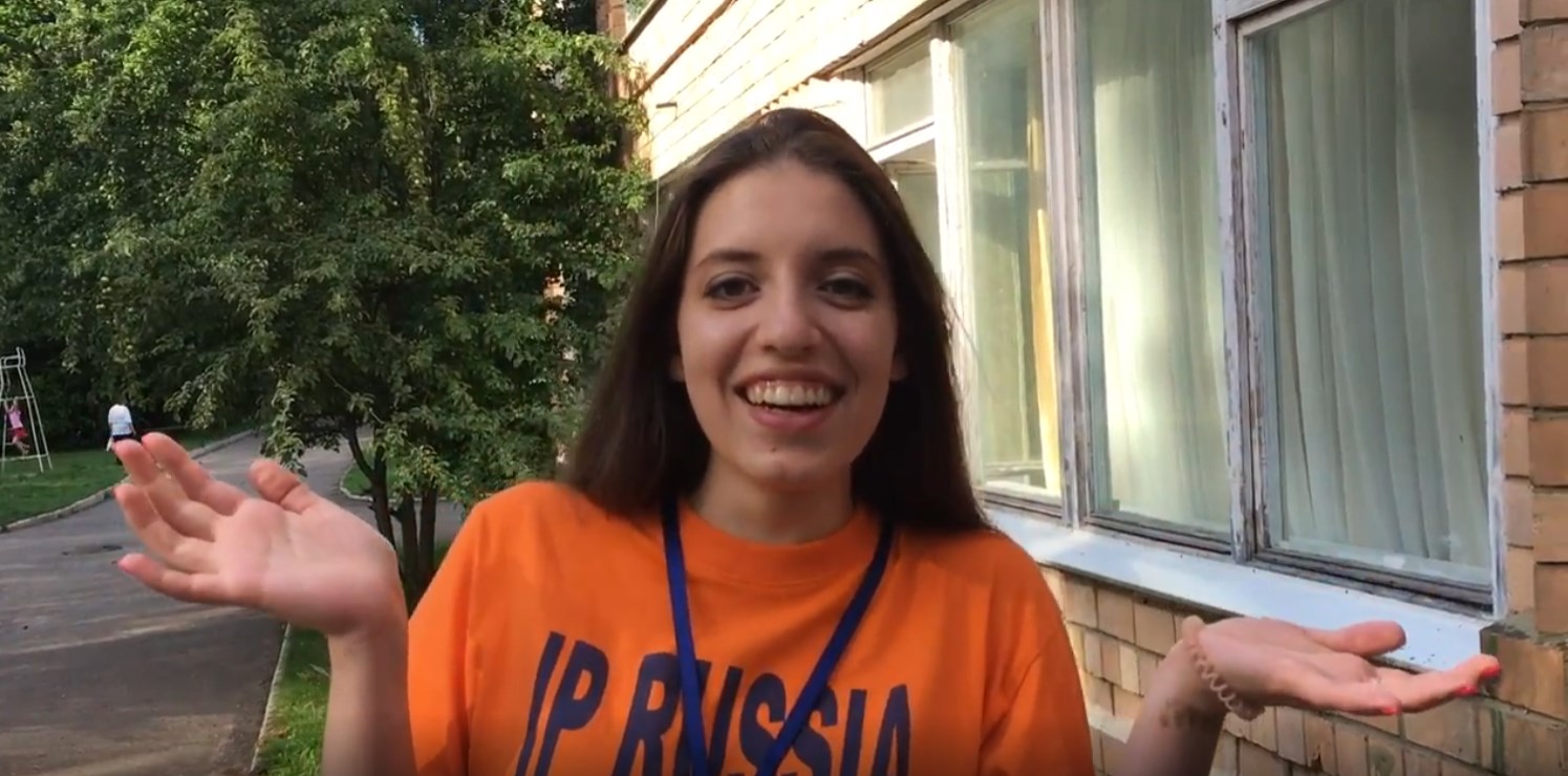 Участница языкового лагеря IP Russia на фоне деревьев у здания.
