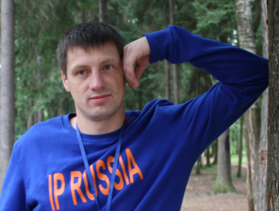 Участник языкового лагеря IP Russia в лесу, одет в синюю кофту, отдыхает на природе.